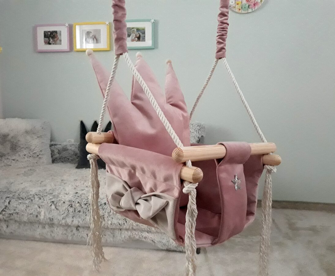 Dusty pink crown-shaped velvet swing with wooden dowels and rope hanging in modern bedroom