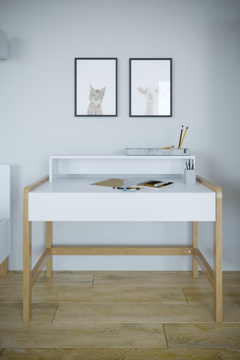 White kids desk with storage shelf and oak legs styled in bedroom with wall art and supplies