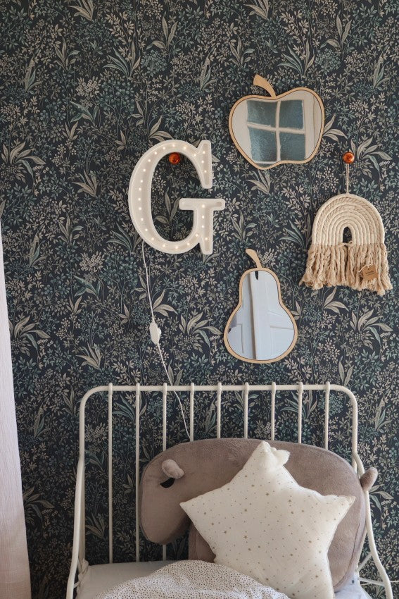 Apple wooden mirror with window design on dark floral wallpaper above white metal bed frame
