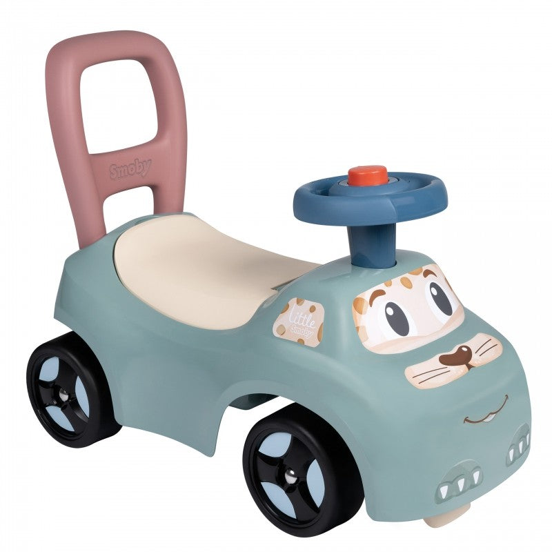Turquoise ride-on pusher with pink handle, removable blue horn, and friendly cartoon face design