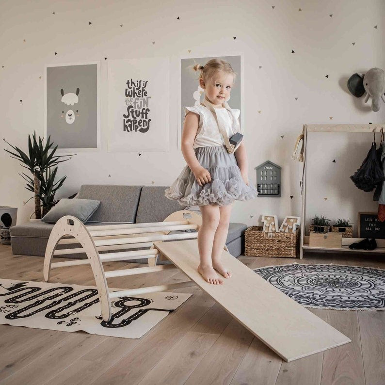 Child walking across ramp attached to natural birch wood climbing arch