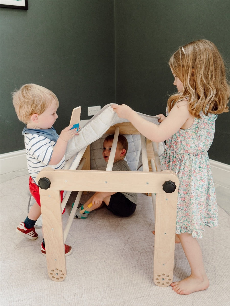 Three children playing together on natural wood Pikler triangle in multiple configurations