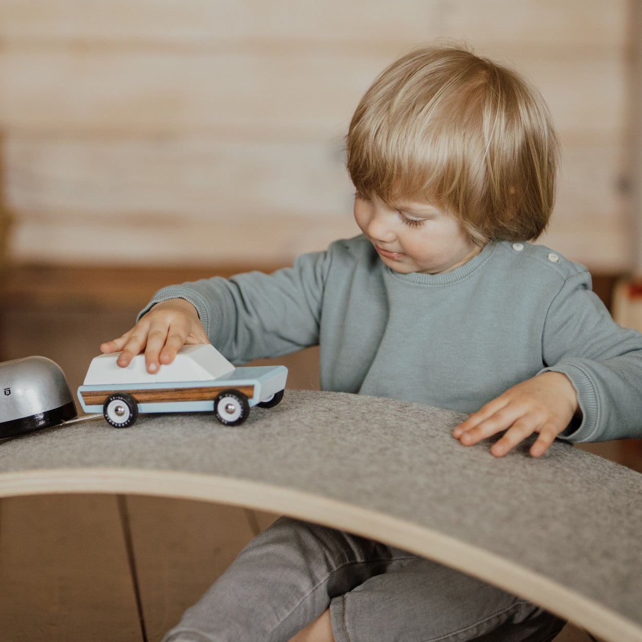 Toddler playing with toy car on grey felt surface of balance board