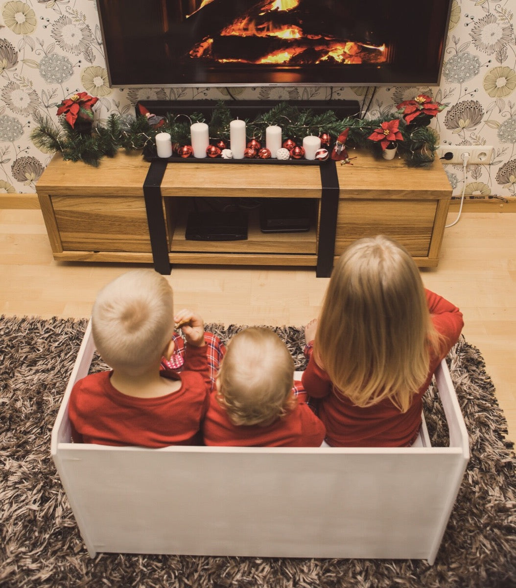 Three young children sitting in white Montessori table bench during holiday gathering