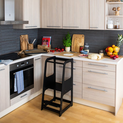 Black helper tower stool positioned at modern kitchen counter with white cabinetry