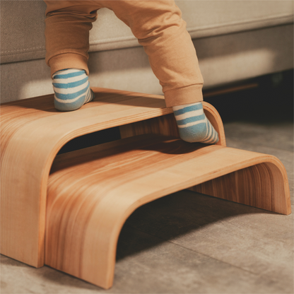 Child's feet on two stacked wooden step stools showing versatile two-in-one design