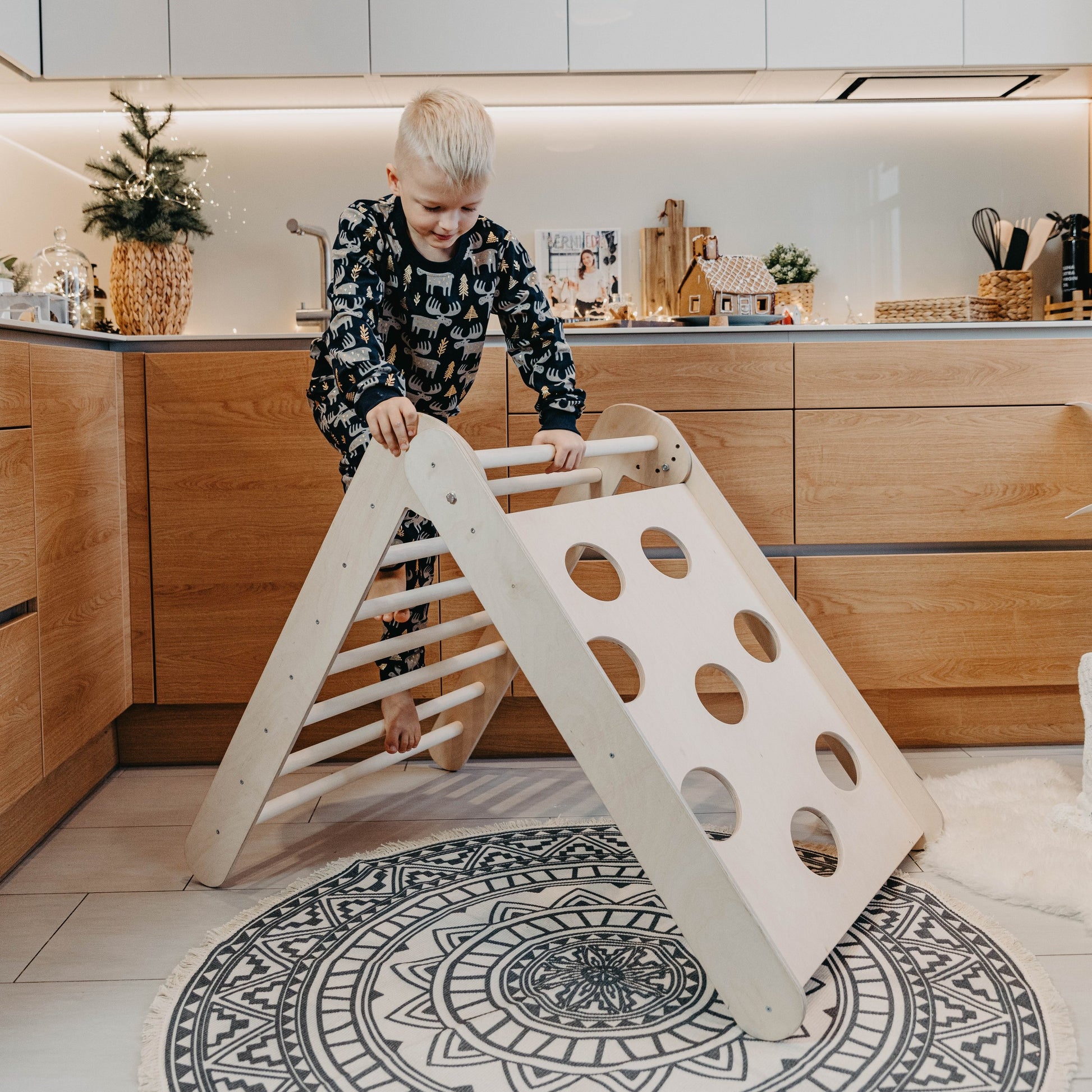Toddler climbing on indoor gym triangle in modern kitchen