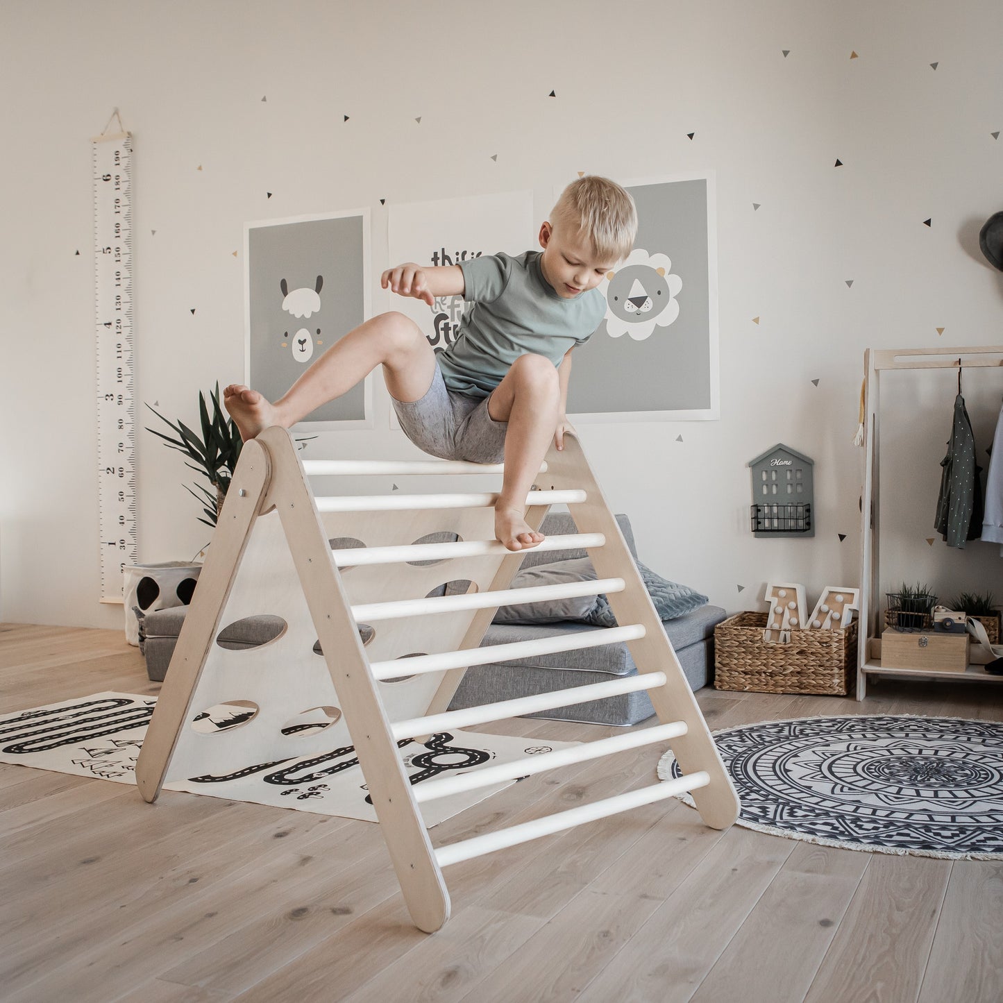 Child climbing steep slope side of wood climbing triangle in playroom