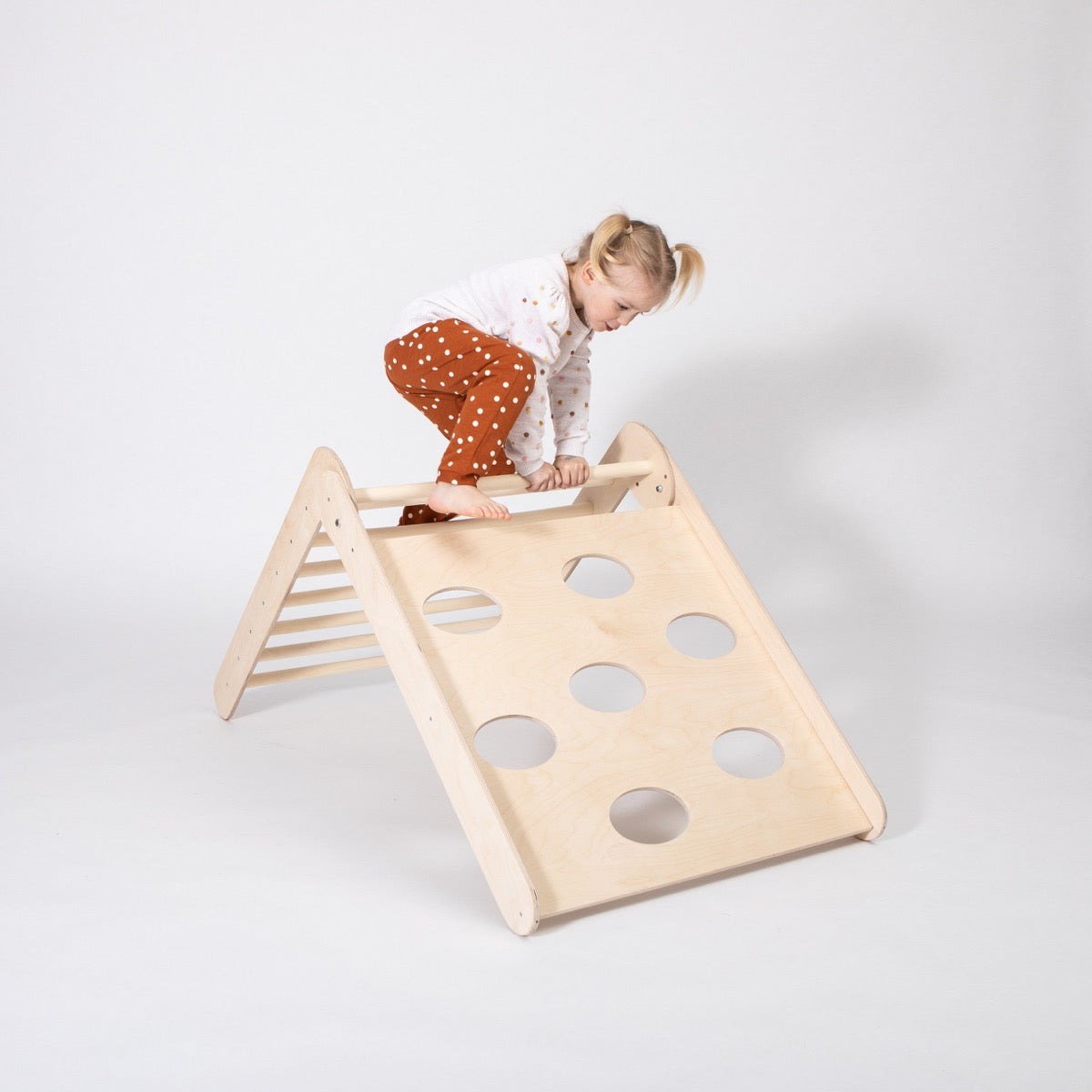 Toddler scaling gentle slope side of wooden 2-in-1 climbing triangle