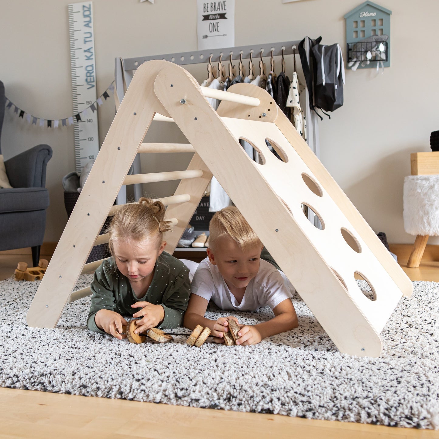Two children playing beneath assembled climbing triangle creating tent-like shelter