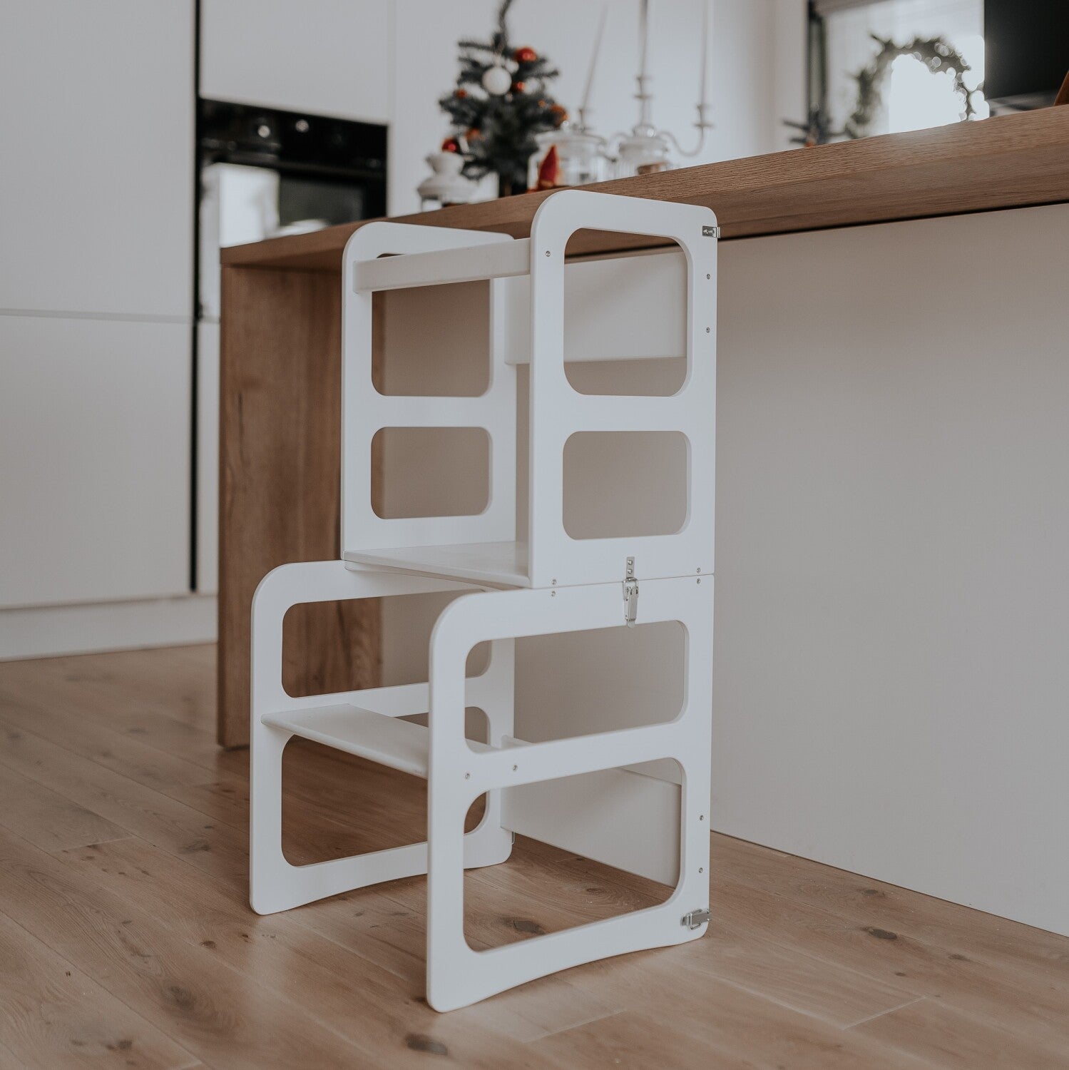 White Montessori kitchen tower stool against kitchen counter showing storage design
