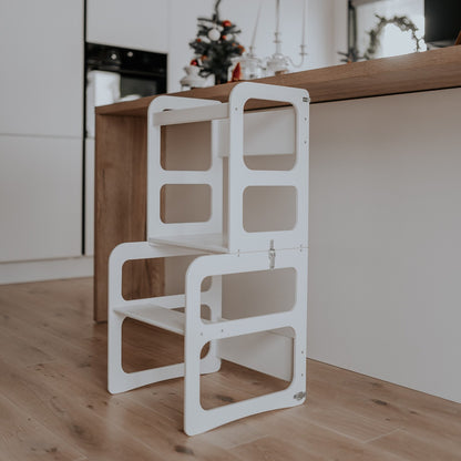 White Montessori kitchen tower stool against kitchen counter showing storage design