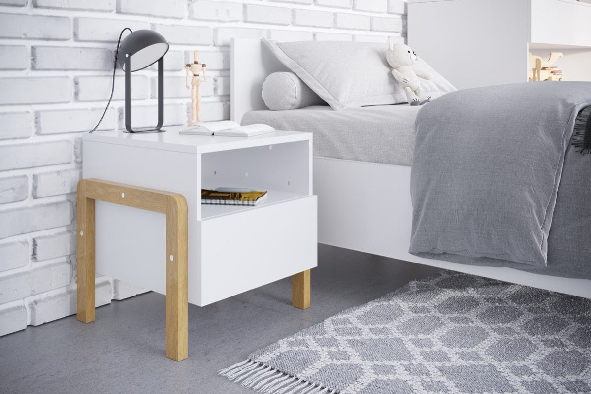 Victor white and oak bedside table styled in a child's bedroom next to a gray upholstered bed