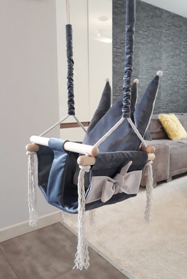 Grey crown shaped children's swing hanging indoors with soft velvet cushion and rope cords