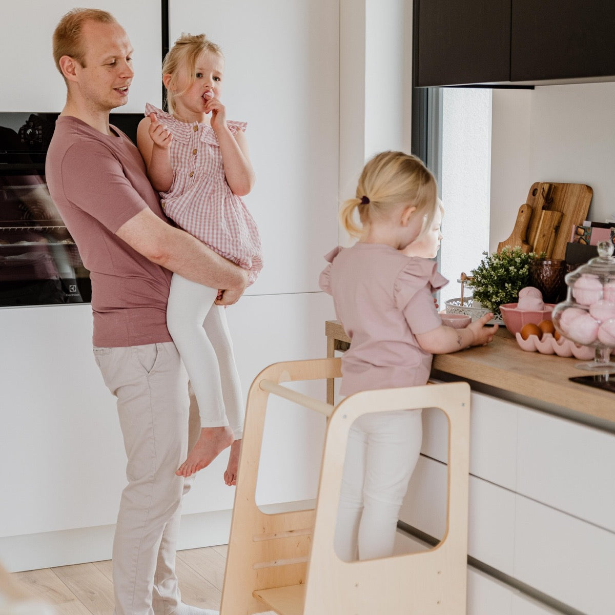 Child using white helper tower stool at kitchen counter for baking activity