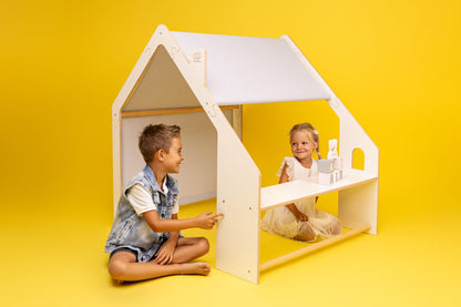 Two children playing inside white wooden house with yellow interior on bright yellow background