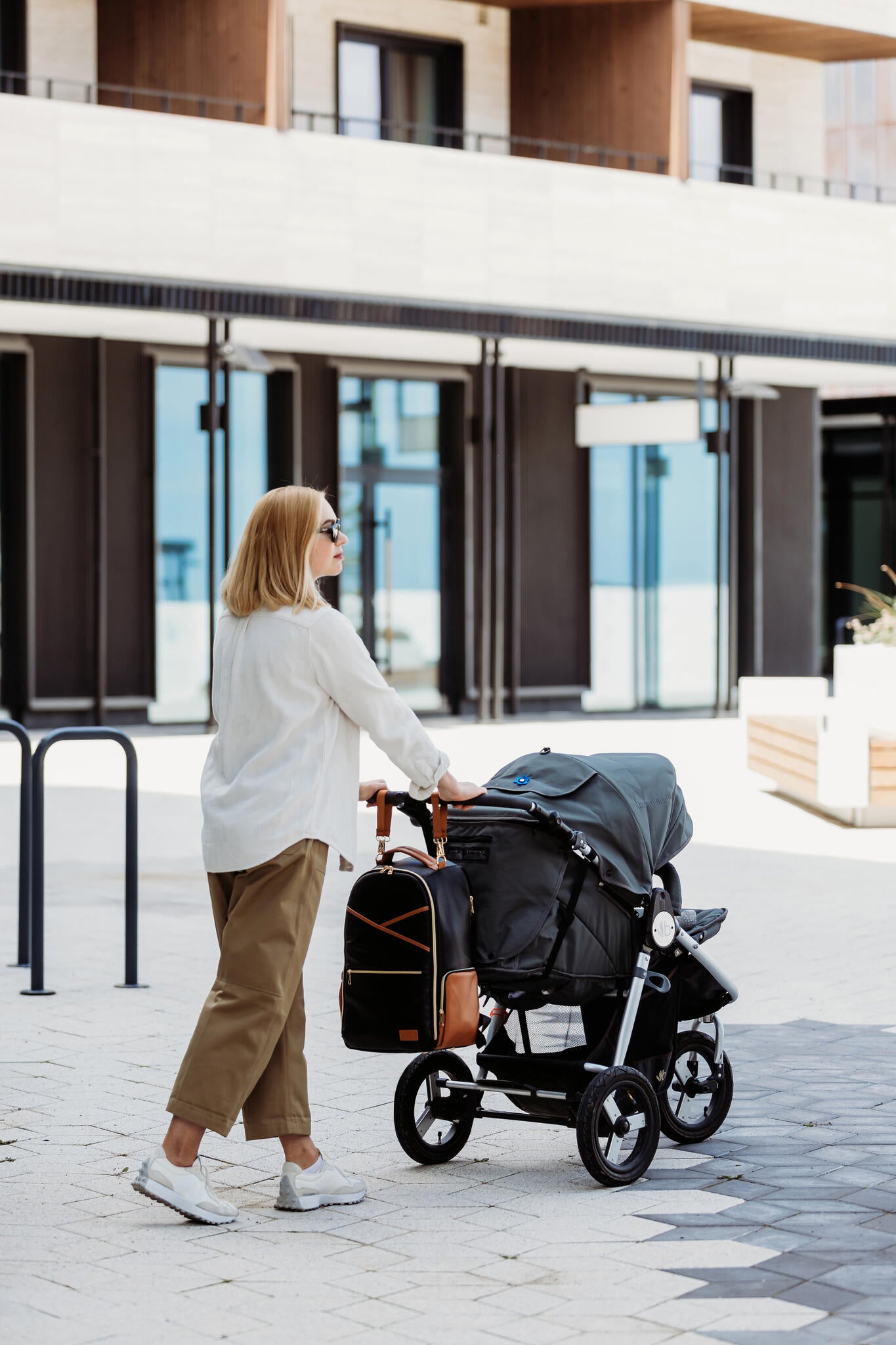 Parent with child exiting building, carrying black coffee large diaper backpack on back