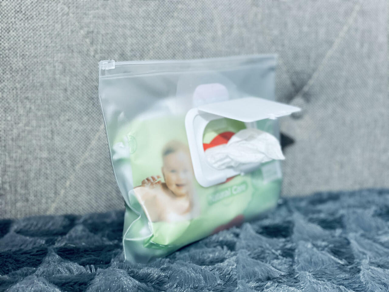 Clear storage pouch with white clasp closure for baby items, inside baby handbag