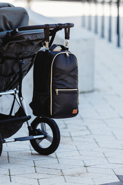 Espresso diaper backpack attached to stroller handle with secure straps