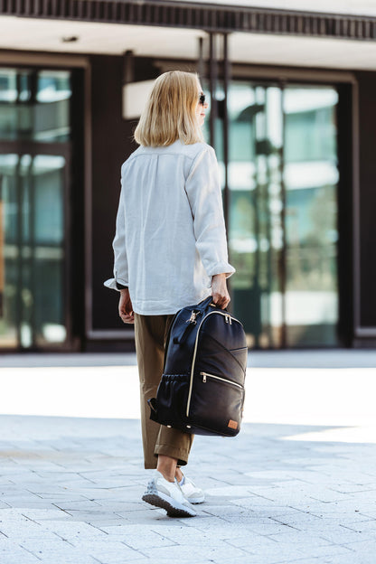 Woman from behind carrying espresso diaper backpack while walking