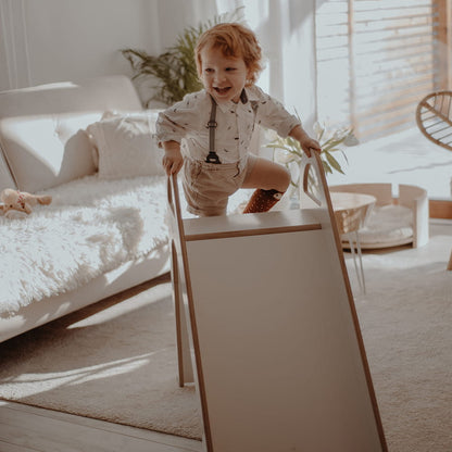 Toddler playing on wooden indoor slide in bright playroom with natural light