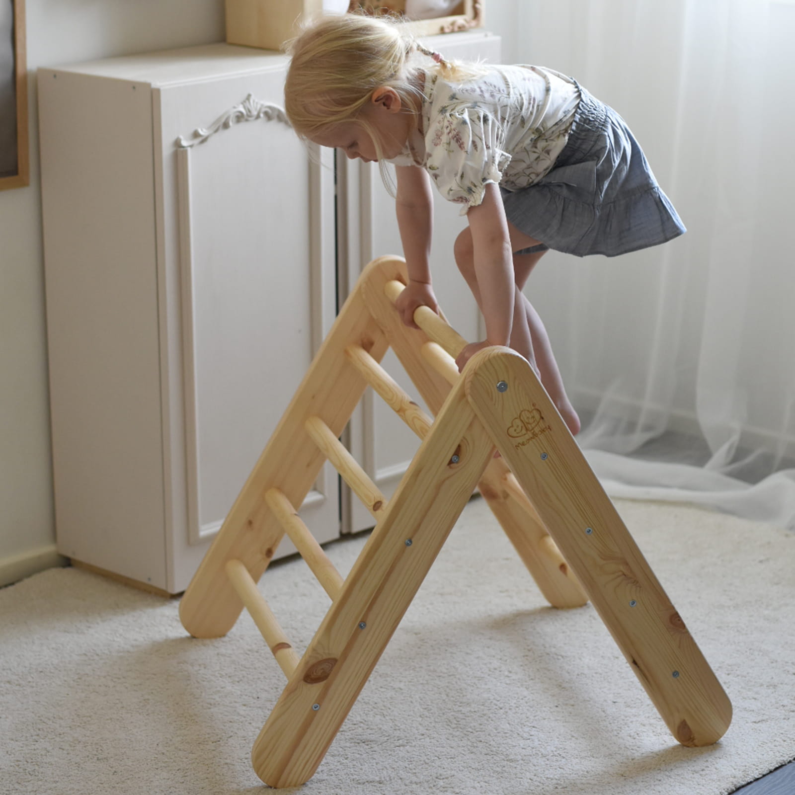 Child climbing natural wood ladder structure with pink tent cover