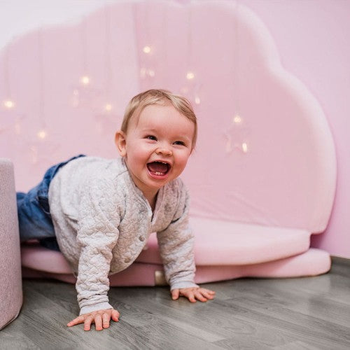 Toddler crawling on pink velvet cloud shaped play mat with fairy lights