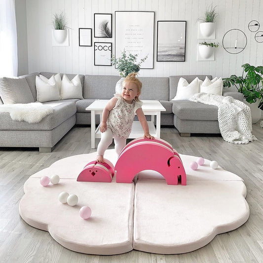 Toddler playing on pink cloud play mat with sensory balls in home