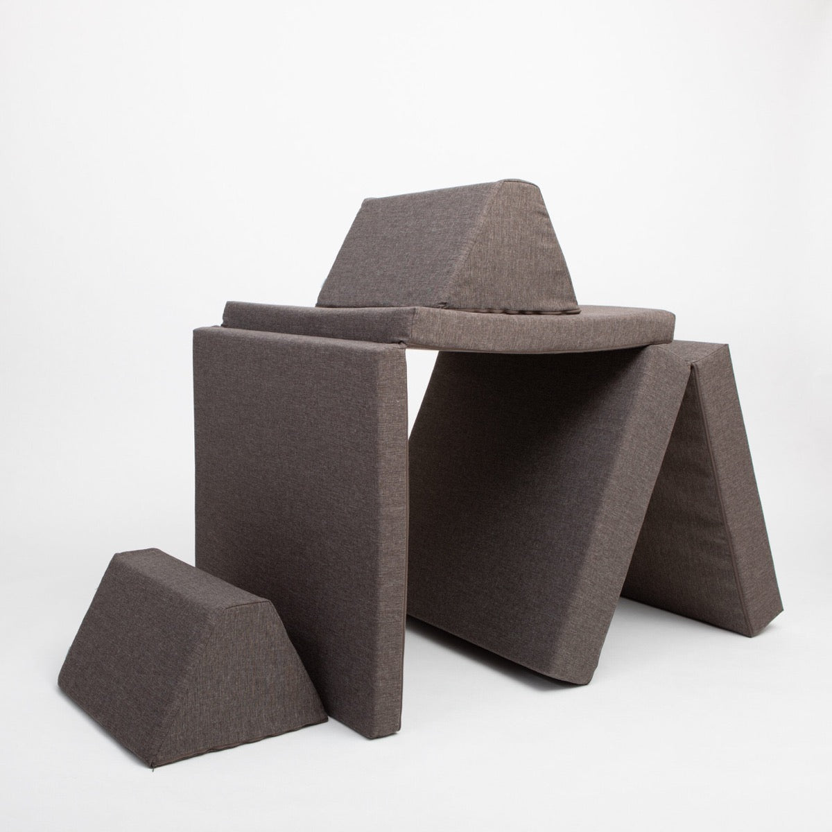 Dark brown modular foam pieces arranged in three-dimensional play structure with tent opening