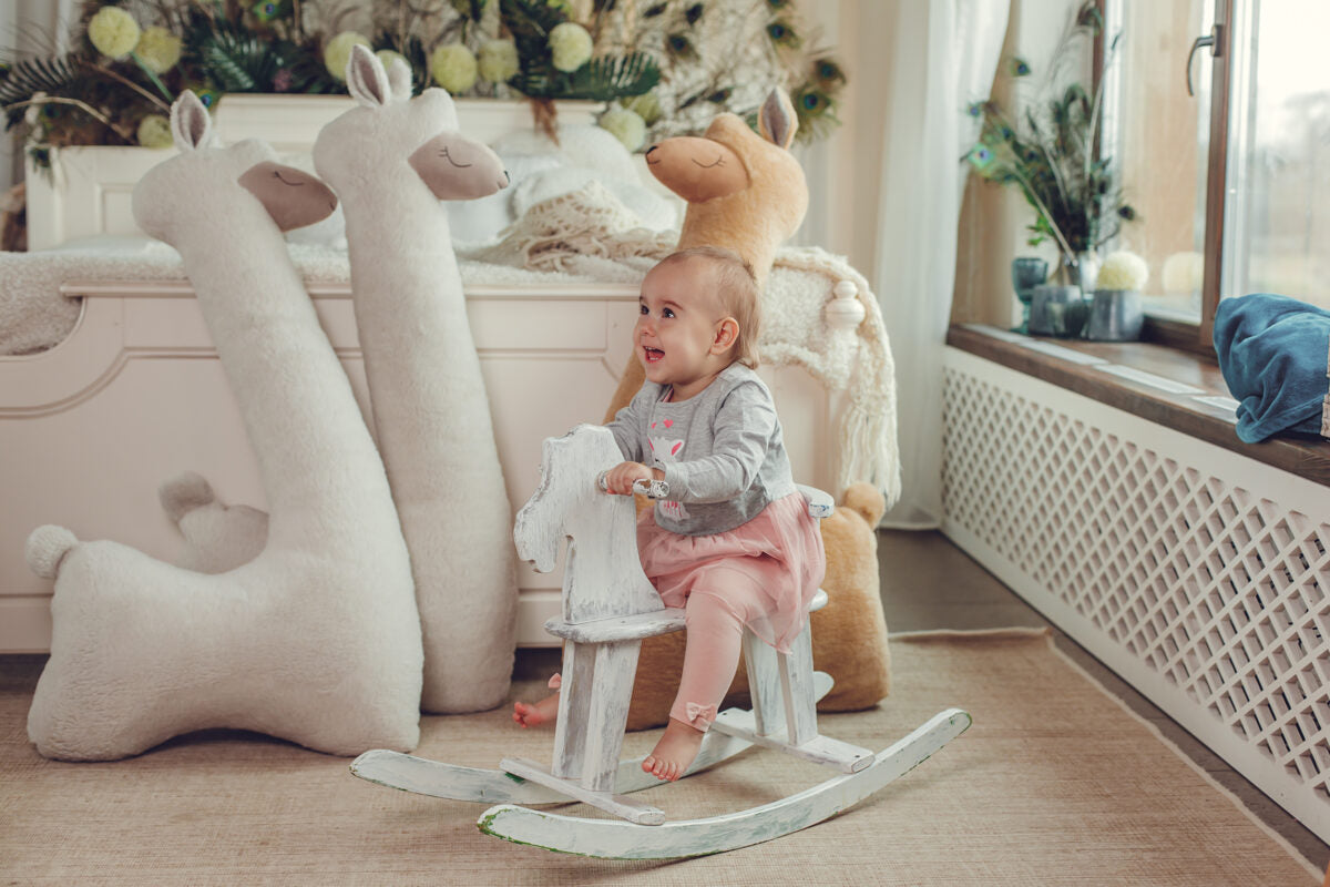 Toddler with giant beige alpaca plush toys – scale reference showing 1m height in playroom
