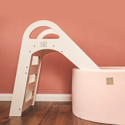 White wooden indoor slide positioned against coral accent wall in playroom
