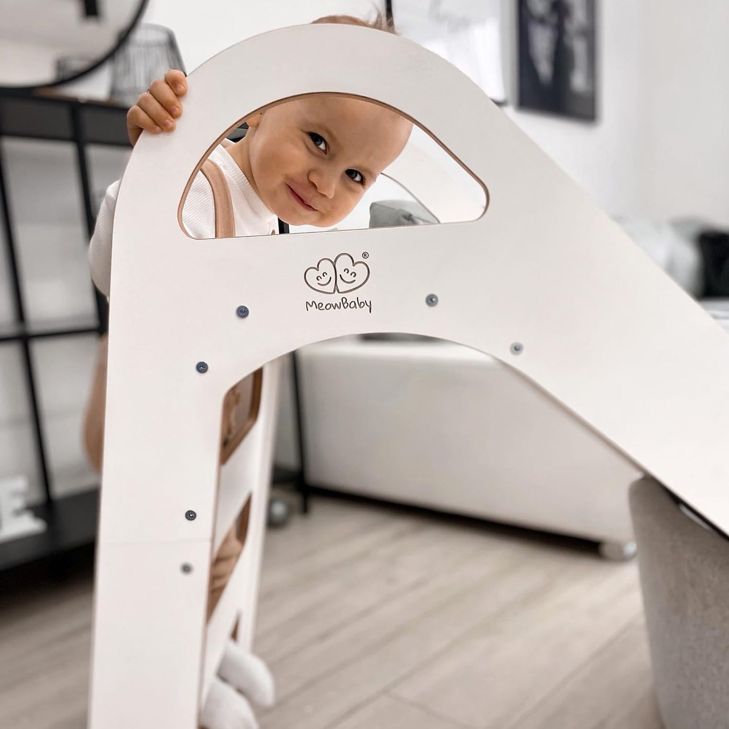 Child peeking through round window on white wooden slide's climbing side