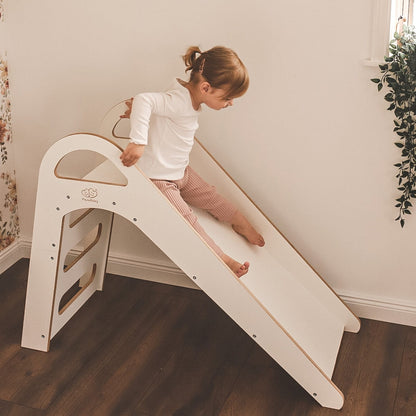 Girl sliding down white wooden Scandi slide with rope grip in modern home