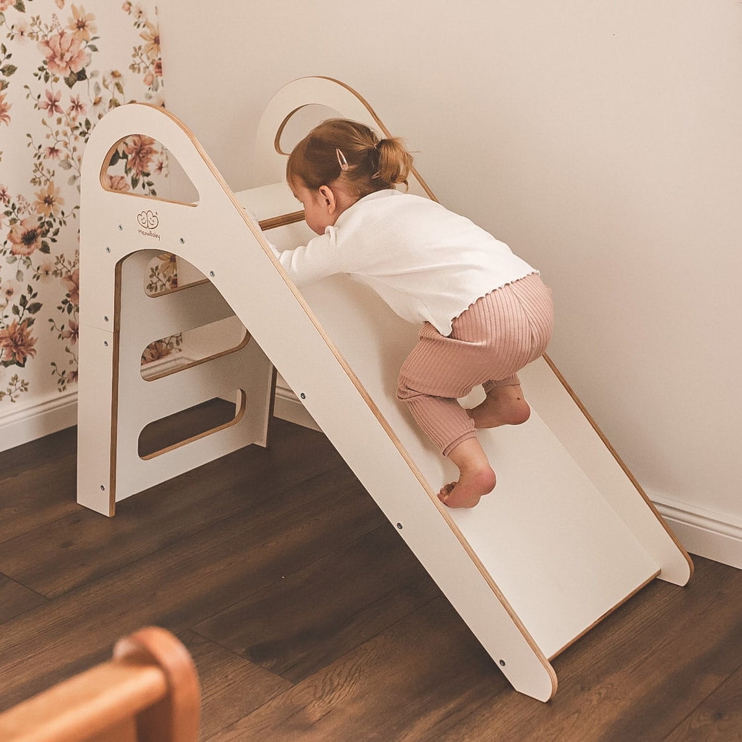 Child playing in colorful ball pit below white wooden Scandi slide
