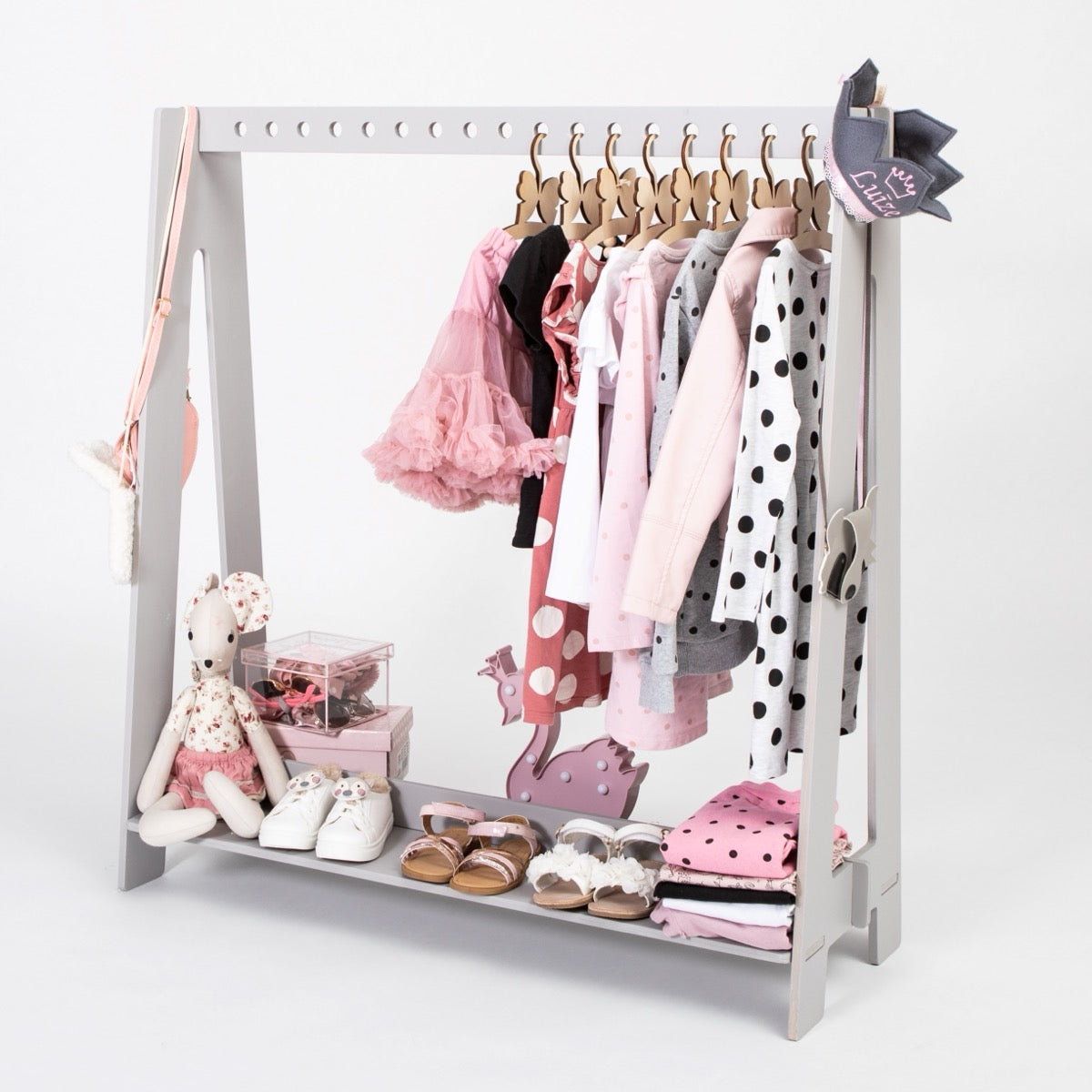 Portable wooden clothing rack with wooden hangers holding colorful toddler outfits