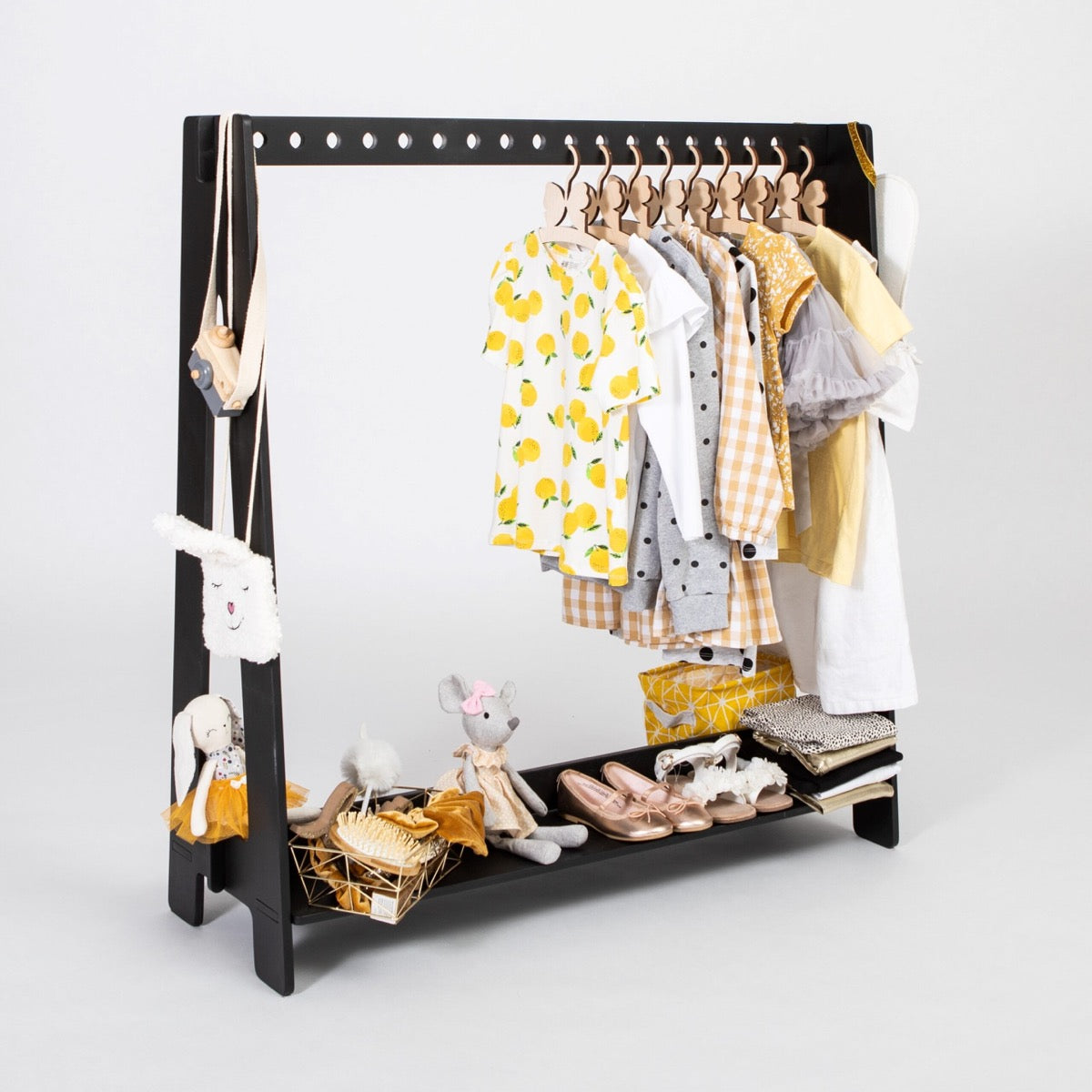 Black birch plywood clothing rack displaying colorful toddler dresses and shoes from front
