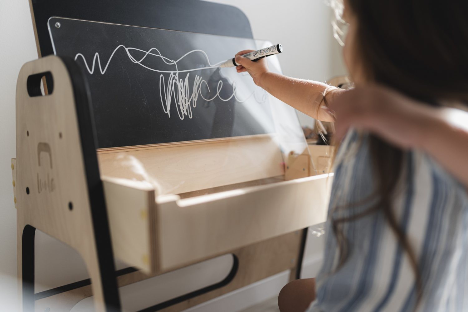 Kid writing on tilted chalkboard surface of Luula Julle table during creative play