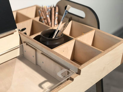 Close-up of table's wooden storage boxes holding pencils, brushes, and supplies