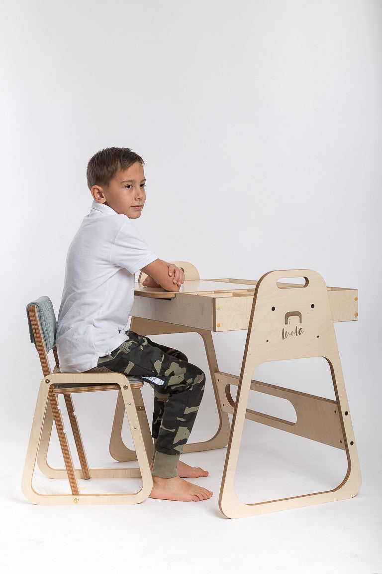 Young boy sitting at Montessori table and chair set while reading