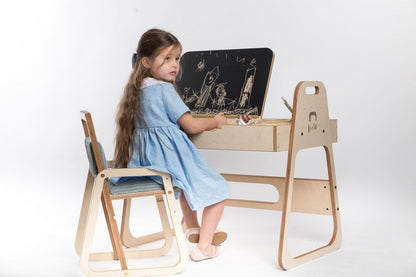 Girl in blue dress drawing on chalkboard panel at Luula Julle table