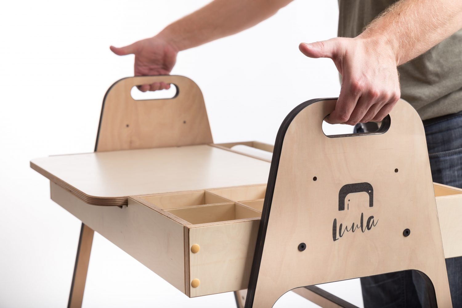 Two hands carrying cannon pink Montessori chair showing portable design and handles