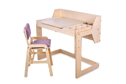 Side view of natural birch Montessori table with lift-top surface and matching chair at workspace