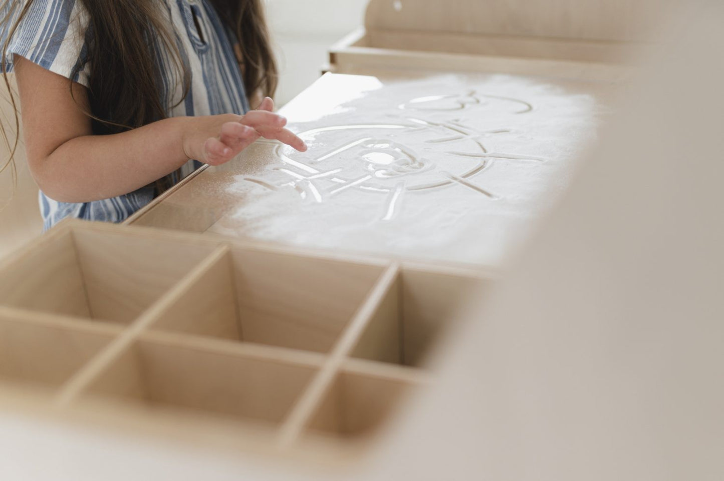 Close-up of child's hand drawing on laminated white table surface