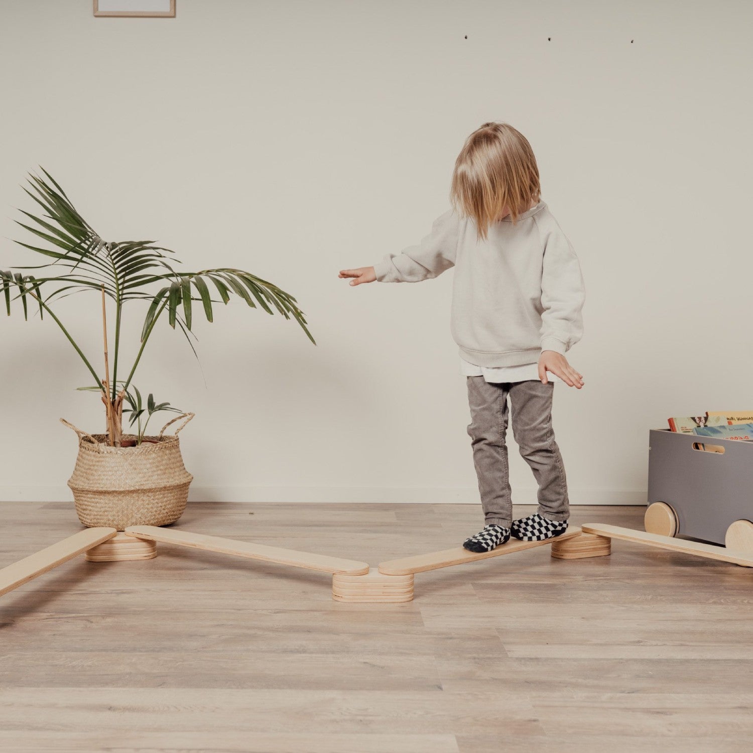 Child walking on wooden balance beam with arms out for stability