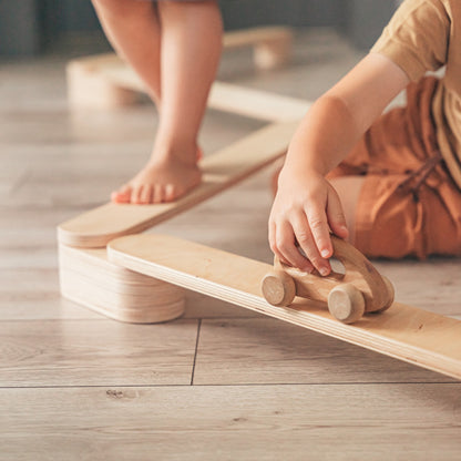 Close-up of child's hands and feet on wooden balance beam during play