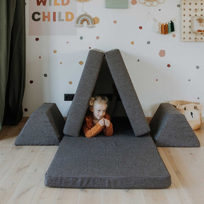 Child playing under dark brown foam A-frame tent structure with base and cushion pieces