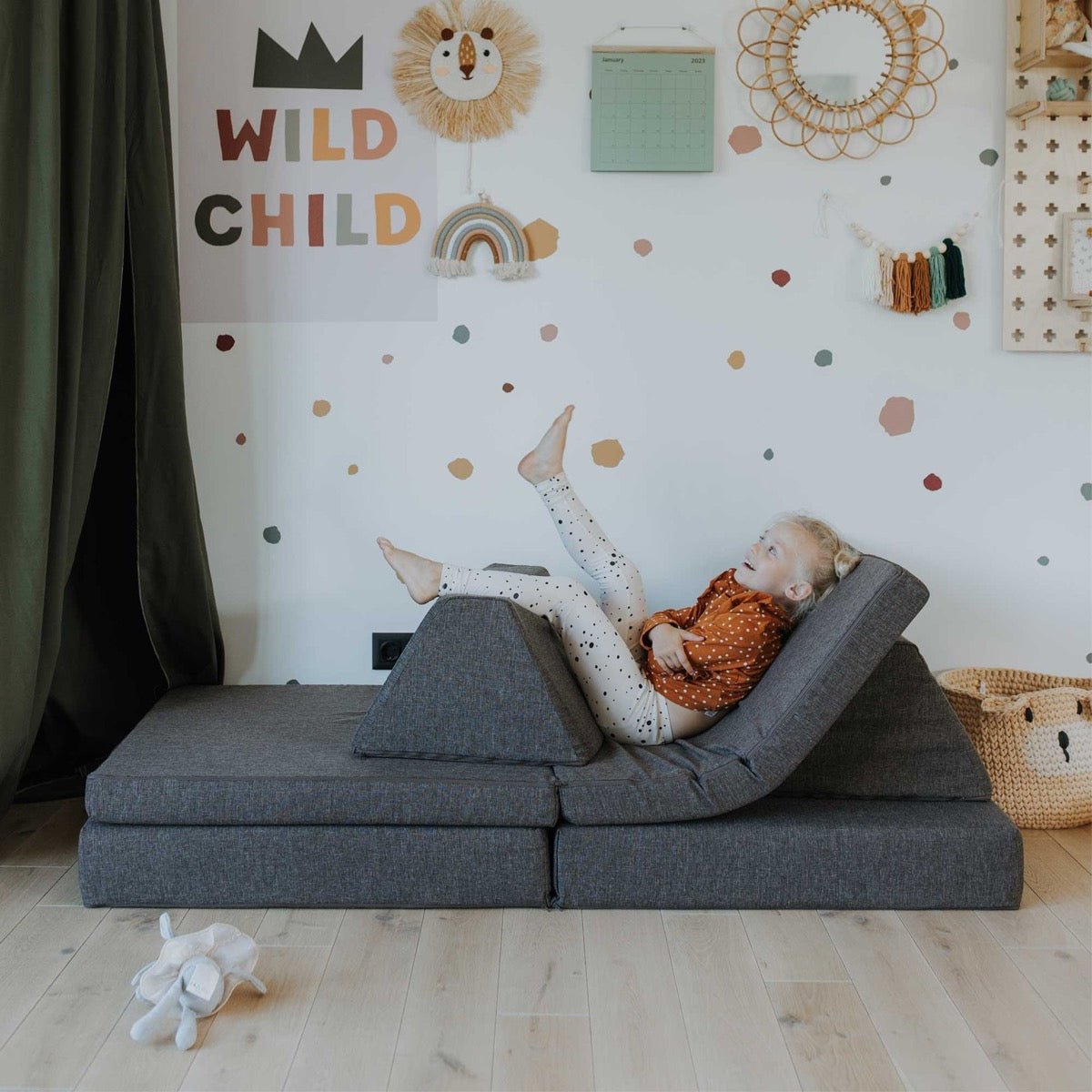 Child relaxing on dark brown foam furniture configured as a low chaise lounge with angled backrest