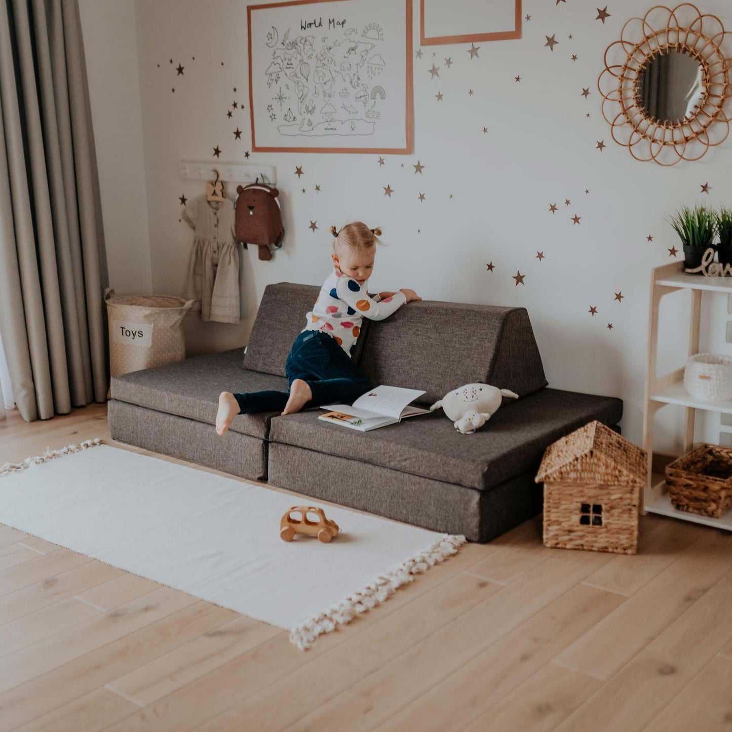 Child reading on dark brown activity play mattress configured with cushions and backrest support