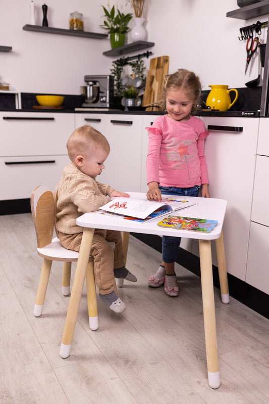 Two toddlers using wooden bunny table and chair set for coloring and drawing in a kitchen