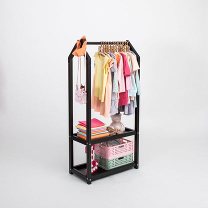 Black metal clothing rack with hanging rod and two storage shelves holding children's clothing